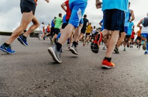 three runners behind large group of people running how to prevent running injuries
